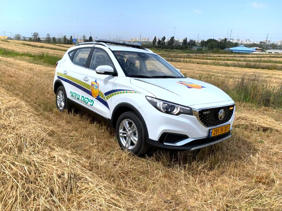 ניידת לפיקוח עירוני חשמלית מסוג MG ZS EV בצבע לבן עם כיתוב של עיריית ראשון לציון בשדה