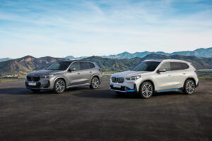 שני רכבי ב.מ.וו iX1 עומדים אחד ליד השני, אחד בצבע לבן והשני באפור בהיר