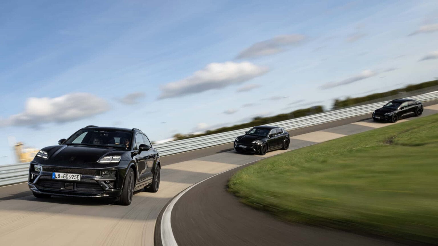 שלושה רכבי פורשה מקאן EV בצבע שחור נוסעים על מסלול מירוצים אחת אחרי השניה