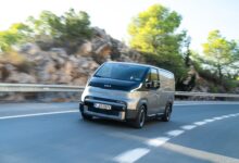 קיה PV5 רכב מסחרי חשמלי בגרסת מטען בצבע אפור פלדה בנסיעה על כביש בינעירוני