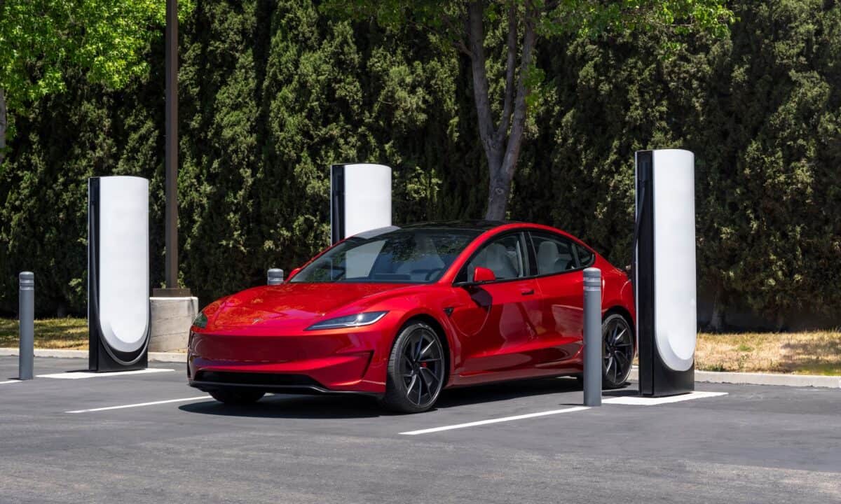 טסלה מודל 3 אדומה מחוברת לעמדת טעינה סופר מהירה של טסלה מסוג V4