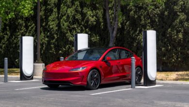 טסלה מודל 3 אדומה מחוברת לעמדת טעינה סופר מהירה של טסלה מסוג V4