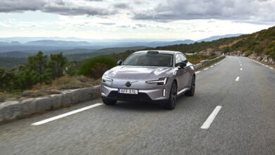 מכונית סאלון וולוו ES90 בצבע אפור נוסעת בכביש בינעירוני בנוף של טבע