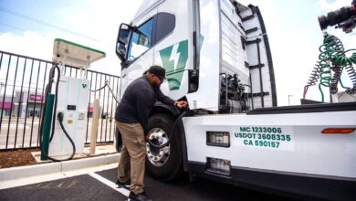 נהג משאית מחבר משאית חשמלית לעמדת טעינה ייעודית